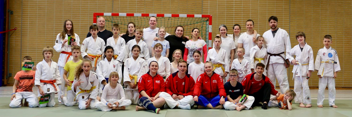 Gruppenfoto von Judokas verschiedener Altersklassen in einer Sporthalle.