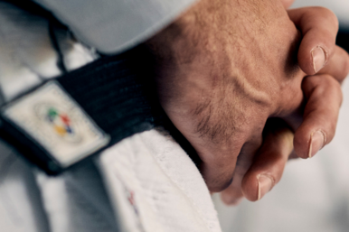 Detailaufnahme von Händen eines männlichen Judokas mit schwarzem Gürtel.