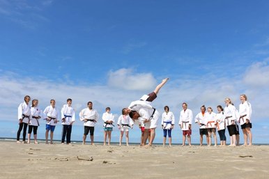 Gruppenfoto am Strand von jugendlichen Judoka. Im Hintergrund ist das Meer.